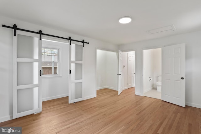 1029 Pennsylvania Ave, Hagerstown, MD 21742 - unfurnished bedroom featuring a barn door, light wood finished floors, and ensuite bathroom