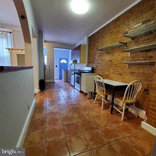 1212 Park Rd NW, Washington, DC 20010 - kitchen with stainless steel appliances, brick wall, and tile patterned floors