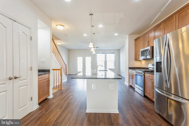 519 Long Wall Dr, Reisterstown, MD 21136 - kitchen featuring appliances with stainless steel finishes, brown cabinets, dark stone countertops, dark wood finished floors, and a center island with sink
