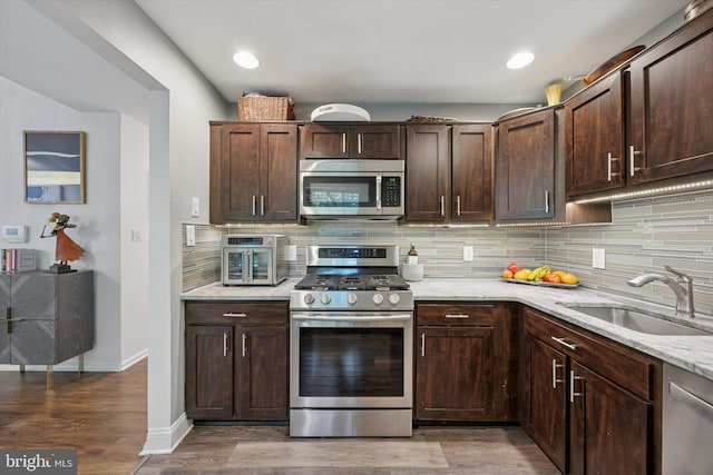 3508 Waltham Ct, Yardley, PA 19067 - kitchen with stainless steel appliances, backsplash, light stone counters, dark brown cabinets, and wood finished floors