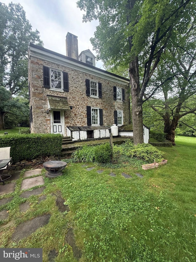 20 Constant Spring Rd, Malvern, PA 19355 - back of house featuring stone siding, a chimney, and a lawn