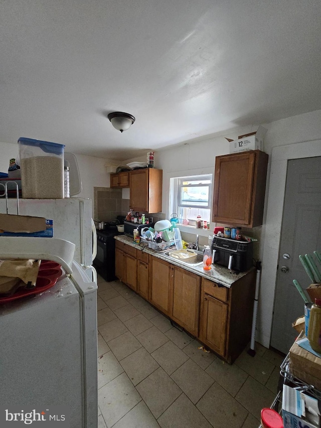 2513 W Sergeant St, Philadelphia, PA 19132 - kitchen featuring brown cabinets, light countertops, light tile patterned floors, and freestanding refrigerator