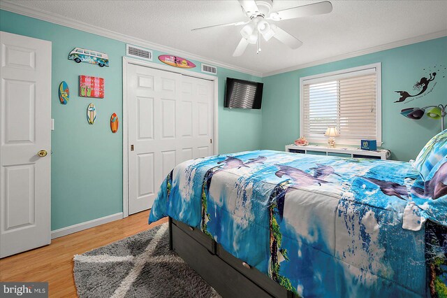 11603 Seaward Rd Unit 6, Ocean City, MD 21842 - bedroom with crown molding, light wood-style floors, a ceiling fan, a closet, and a textured ceiling