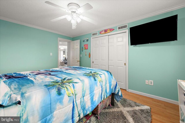 11603 Seaward Rd Unit 6, Ocean City, MD 21842 - bedroom featuring ornamental molding, light wood-style flooring, a closet, a ceiling fan, and a textured ceiling