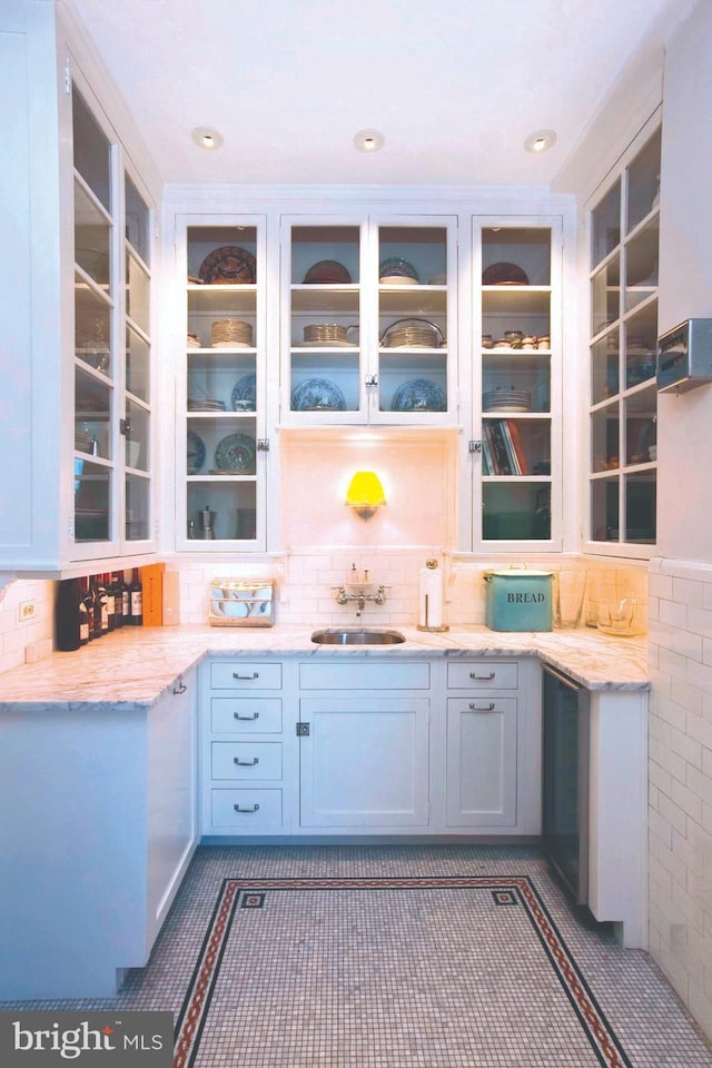 237 S 18th St Unit 20A, Philadelphia, PA 19103 - kitchen featuring a sink, glass insert cabinets, light stone counters, and backsplash