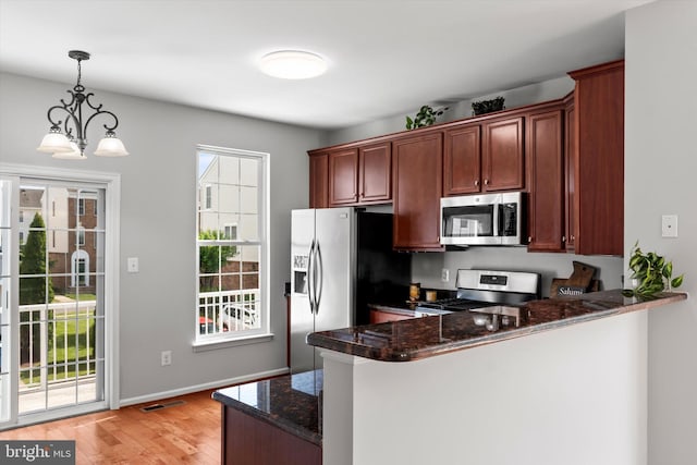 42806 Longworth Ter, Chantilly, VA 20152 - kitchen with appliances with stainless steel finishes, light wood-style floors, a peninsula, hanging light fixtures, and dark stone countertops