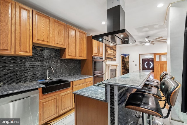3737 N 18th St, Philadelphia, PA 19140 - kitchen featuring island exhaust hood, stainless steel appliances, a sink, a breakfast bar, and decorative backsplash