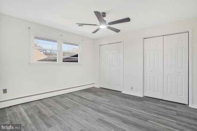 5917 Linthicum Ln, Linthicum Heights, MD 21090 - unfurnished bedroom with baseboard heating, multiple closets, wood finished floors, and ceiling fan