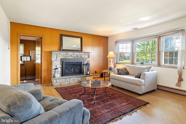 1540 Davidson Rd, Abington, PA 19001 - living area with a baseboard heating unit, wood finished floors, wooden walls, a stone fireplace, and baseboard heating