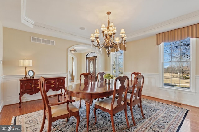 2573 Muirfield Way, Lansdale, PA 19446 - dining area featuring arched walkways, a chandelier, wainscoting, light wood finished floors, and ornamental molding