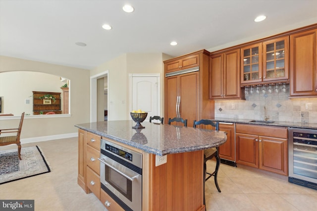 2573 Muirfield Way, Lansdale, PA 19446 - kitchen featuring wine cooler, a breakfast bar area, a center island, arched walkways, and dark stone countertops