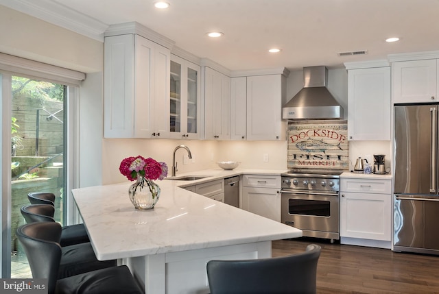 16 Spa Creek Lndg, Annapolis, MD 21403 - kitchen with high quality appliances, wall chimney exhaust hood, a peninsula, white cabinets, and recessed lighting