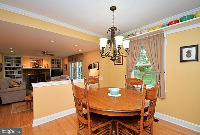 403 Grenoble Dr, Sellersville, PA 18960 - dining space featuring a fireplace, a chandelier, crown molding, light wood-style flooring, and a ceiling fan