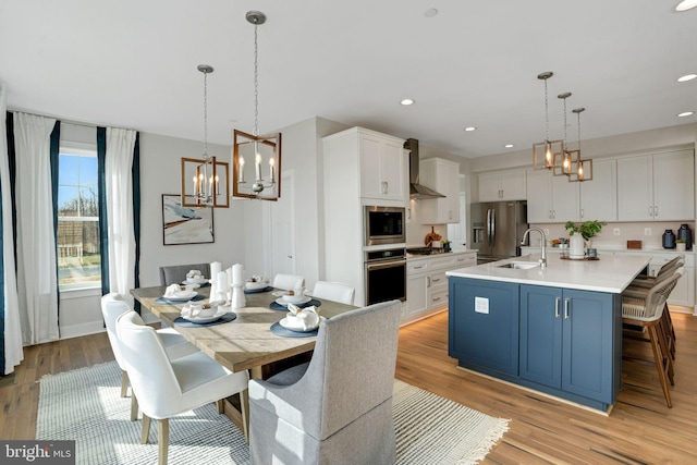 Deer Park Rd, Reisterstown, MD 21136 - kitchen with appliances with stainless steel finishes, a sink, wall chimney range hood, a chandelier, and white cabinetry