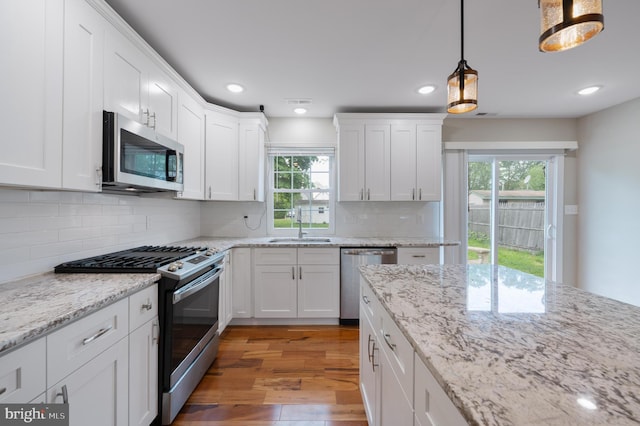 57 Jarvis St, Pemberton, NJ 08068 - kitchen featuring appliances with stainless steel finishes, a sink, light wood finished floors, white cabinetry, and hanging light fixtures