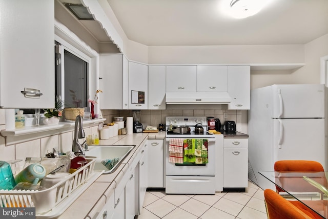 6602 8th Ave, Hyattsville, MD 20783 - kitchen featuring white appliances, under cabinet range hood, white cabinets, light tile patterned floors, and decorative backsplash