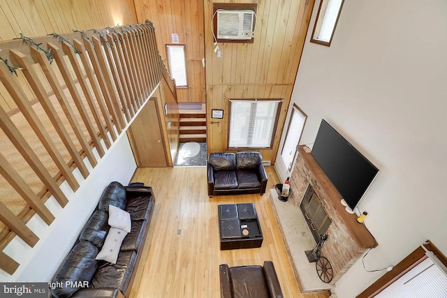 138 Banbury Dr, Bushkill, PA 18324 - living room with wood finished floors, stairway, wooden walls, a towering ceiling, and a wall mounted air conditioner