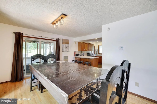 138 Banbury Dr, Bushkill, PA 18324 - dining room with light wood-style flooring, a textured ceiling, and baseboards