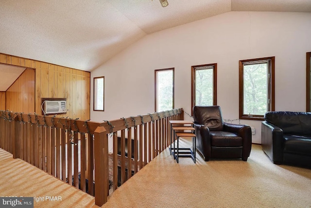 138 Banbury Dr, Bushkill, PA 18324 - living area with vaulted ceiling, carpet flooring, a wall unit AC, an upstairs landing, and wooden walls