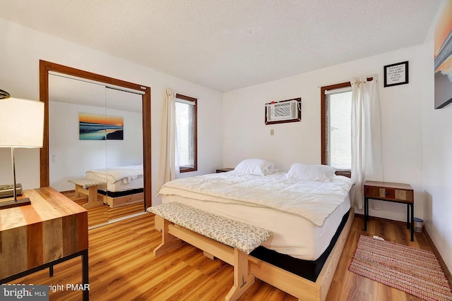 138 Banbury Dr, Bushkill, PA 18324 - bedroom featuring multiple windows, a closet, light wood finished floors, a textured ceiling, and a wall mounted air conditioner