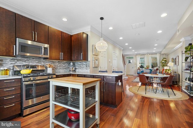 1917 H St NE, Washington, DC 20002 - kitchen featuring stainless steel appliances, a peninsula, ornamental molding, wood finished floors, and open floor plan
