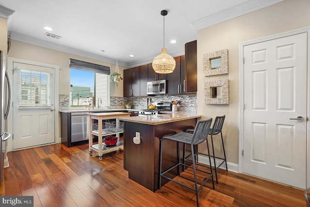 1917 H St NE, Washington, DC 20002 - kitchen featuring stainless steel appliances, ornamental molding, a kitchen breakfast bar, decorative backsplash, and a peninsula