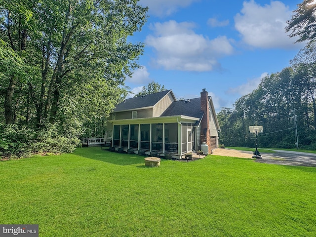 14371 Bristow Rd, Manassas, VA 20112 - rear view of house with concrete driveway, a sunroom, a chimney, and a lawn