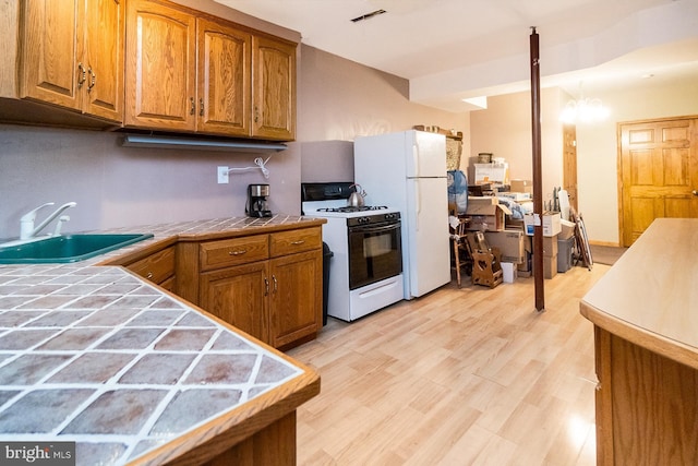 7600 Pohopoco Dr, Kunkletown, PA 18058 - kitchen with white appliances, tile countertops, a sink, brown cabinetry, and light wood-style floors