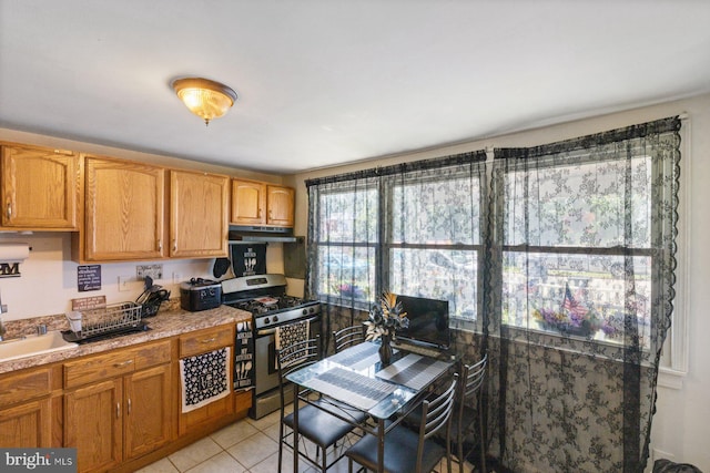 3109 Bero Rd, Halethorpe, MD 21227 - kitchen with stainless steel gas stove, under cabinet range hood, light countertops, and light tile patterned floors
