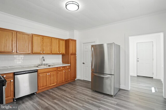 2105 Maisel St, Baltimore, MD 21230 - kitchen featuring stainless steel appliances, light countertops, crown molding, wood finished floors, and brown cabinetry