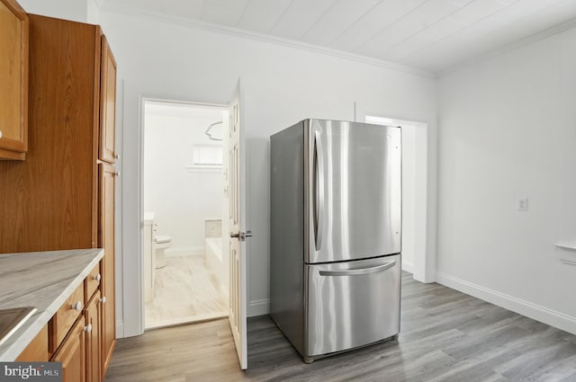 2105 Maisel St, Baltimore, MD 21230 - kitchen with freestanding refrigerator, crown molding, brown cabinetry, light wood finished floors, and light countertops