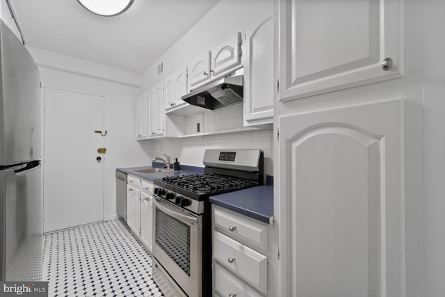 4201 Cathedral Ave NW Unit 303E, Washington, DC 20016 - kitchen with stainless steel appliances, under cabinet range hood, dark countertops, white cabinetry, and tasteful backsplash