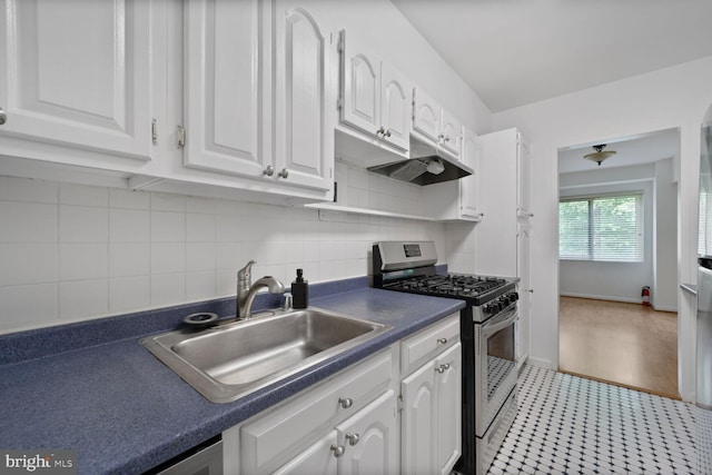 4201 Cathedral Ave NW Unit 303E, Washington, DC 20016 - kitchen with gas stove, white cabinets, dark countertops, under cabinet range hood, and backsplash