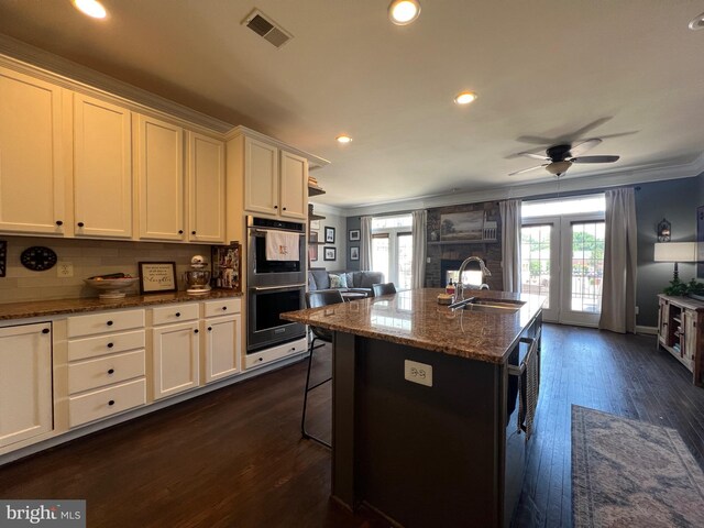 13755 Tides St, Woodbridge, VA 22191 - kitchen with stainless steel double oven, crown molding, open floor plan, dark wood-type flooring, and a breakfast bar