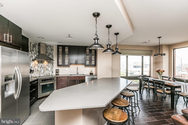 10 E Lee St Unit 1209, Baltimore, MD 21202 - kitchen featuring stainless steel appliances, wall chimney range hood, a center island, a breakfast bar, and glass insert cabinets