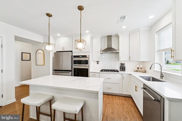 512 S Media Way, Media, PA 19063 - kitchen with wall chimney range hood, appliances with stainless steel finishes, decorative backsplash, light wood-style flooring, and white cabinetry