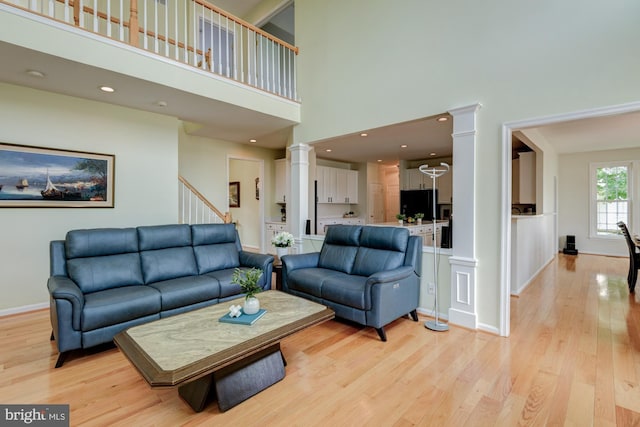 213 Casper Way, Middletown, DE 19709 - living area with decorative columns, a towering ceiling, light wood-style flooring, and stairway
