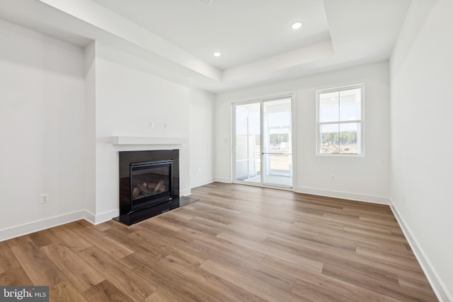 19712 Crows Nest Ct, Georgetown, DE 19947 - unfurnished living room featuring light wood-type flooring, a tray ceiling, a glass covered fireplace, baseboards, and recessed lighting