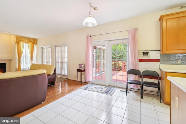 2363 Ashford Dr, Waldorf, MD 20603 - kitchen with french doors, open floor plan, light countertops, a lit fireplace, and light brown cabinets