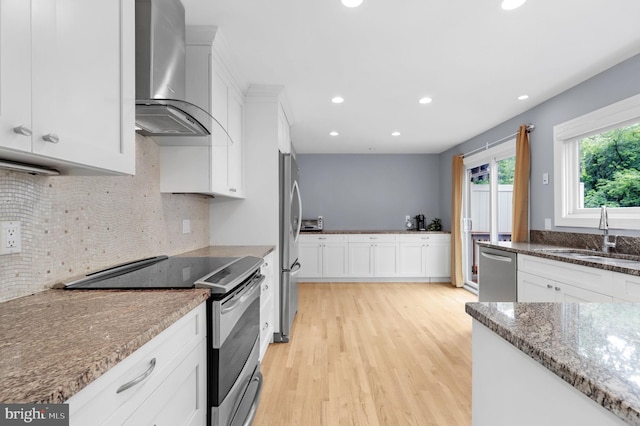 6430 Wishbone Ter, Cabin John, MD 20818 - kitchen featuring appliances with stainless steel finishes, wall chimney exhaust hood, light wood-style floors, recessed lighting, and white cabinetry