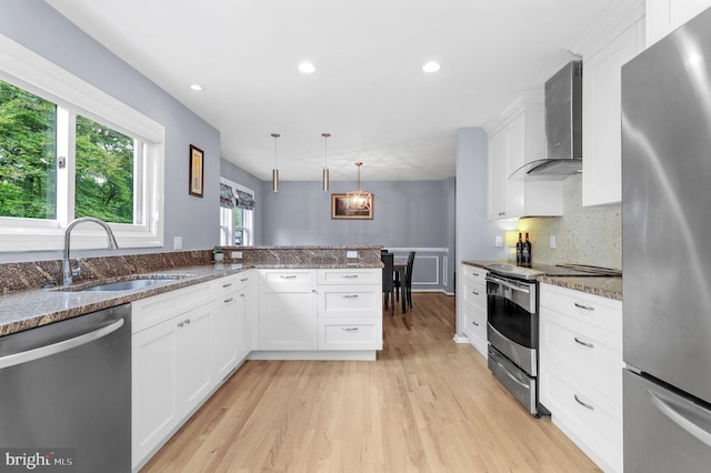 6430 Wishbone Ter, Cabin John, MD 20818 - kitchen with stainless steel appliances, wall chimney exhaust hood, white cabinets, light wood-style floors, and decorative light fixtures