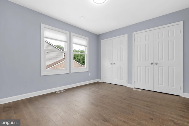 6430 Wishbone Ter, Cabin John, MD 20818 - unfurnished bedroom featuring multiple closets and dark wood-type flooring