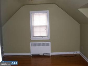 additional living space featuring radiator, wood finished floors, and lofted ceiling