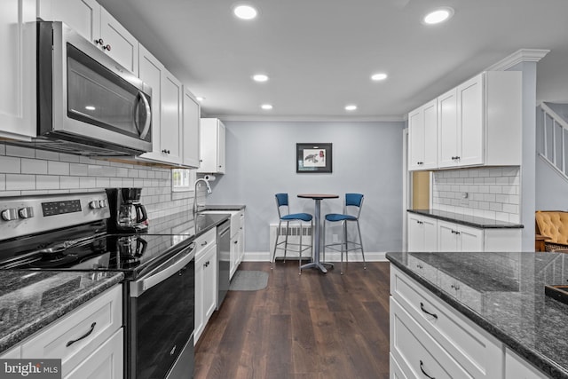 440 E Magnolia Dr, Morrisville, PA 19067 - kitchen with stainless steel appliances, recessed lighting, white cabinets, crown molding, and dark stone counters