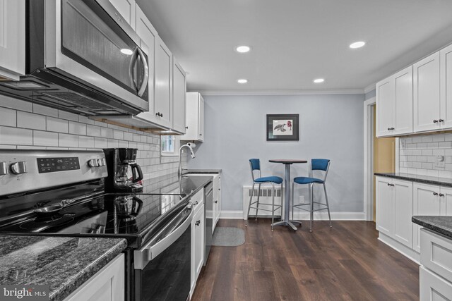 440 E Magnolia Dr, Morrisville, PA 19067 - kitchen with appliances with stainless steel finishes, decorative backsplash, ornamental molding, white cabinetry, and dark wood-type flooring