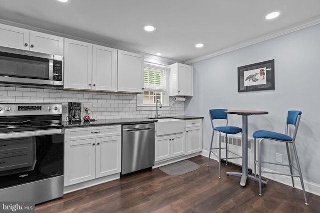 440 E Magnolia Dr, Morrisville, PA 19067 - kitchen featuring appliances with stainless steel finishes, ornamental molding, tasteful backsplash, white cabinets, and dark wood-style flooring
