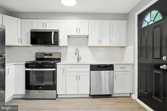 8206 Boundary, Baltimore, MD 21222 - kitchen featuring appliances with stainless steel finishes, light countertops, white cabinetry, and light wood-type flooring