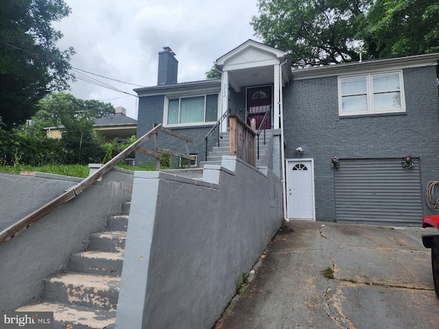 5702 Landover Rd, Hyattsville, MD 20784 - view of front of house with brick siding, a garage, a chimney, stairway, and driveway