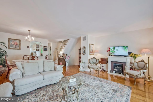 1312 Cedar Park Rd, Annapolis, MD 21401 - living room with stairs, a chandelier, a glass covered fireplace, and wood finished floors