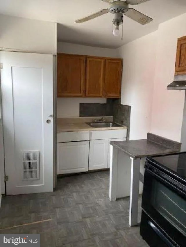 1720 1st St NW, Washington, DC 20001 - kitchen featuring black range with electric cooktop, wall chimney exhaust hood, a ceiling fan, and brown cabinets